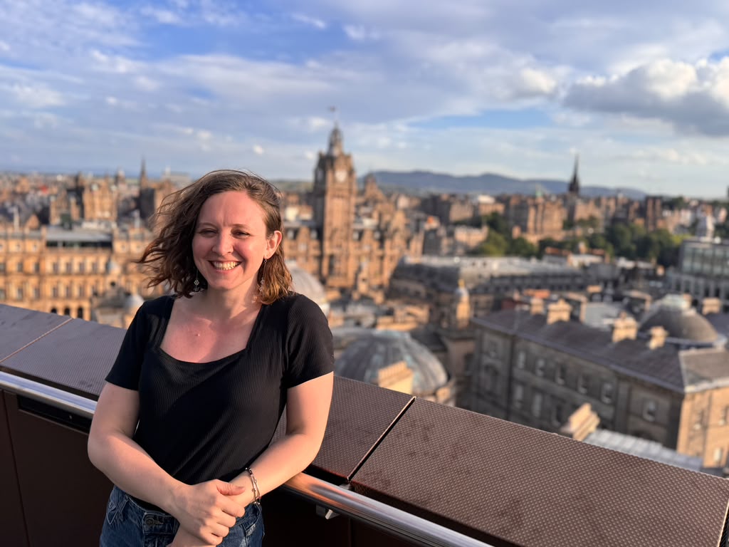 Anna Ball, smiling, with the Edinburgh skyline behind her